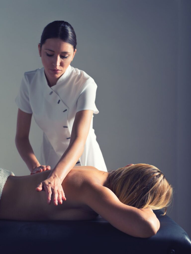 여자마사지 관리사가 누워있는 손님의 등 마사지를 하는 장면